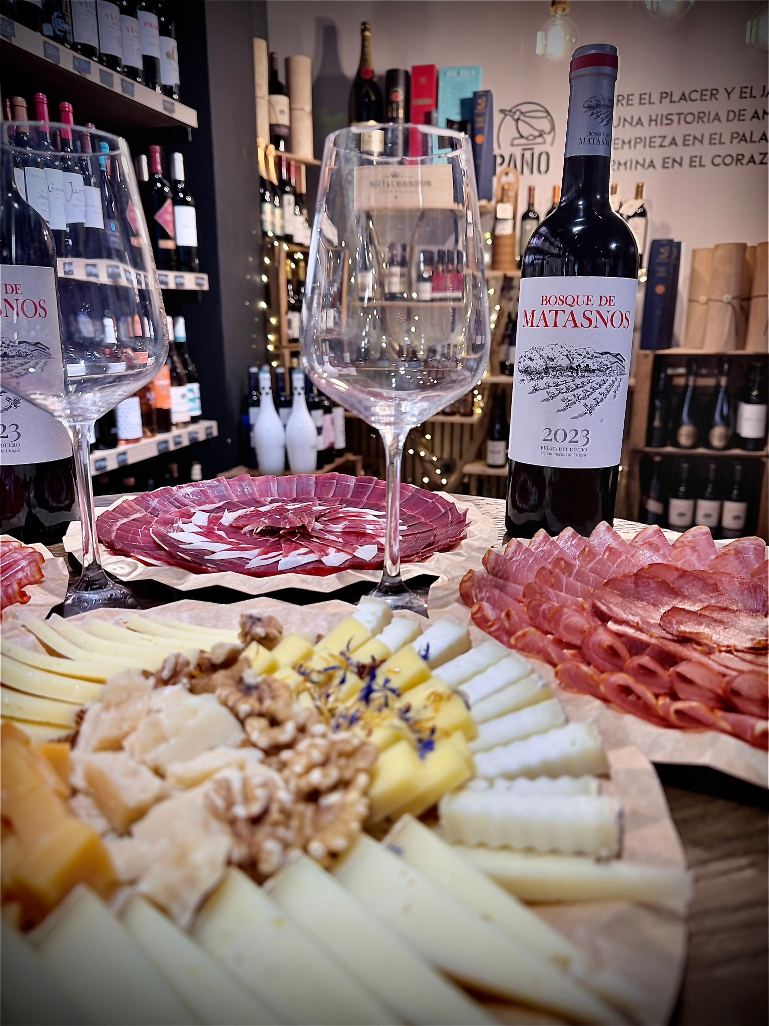 Copas de vino junto a tabla de ibéricos y quesos en El Apaño